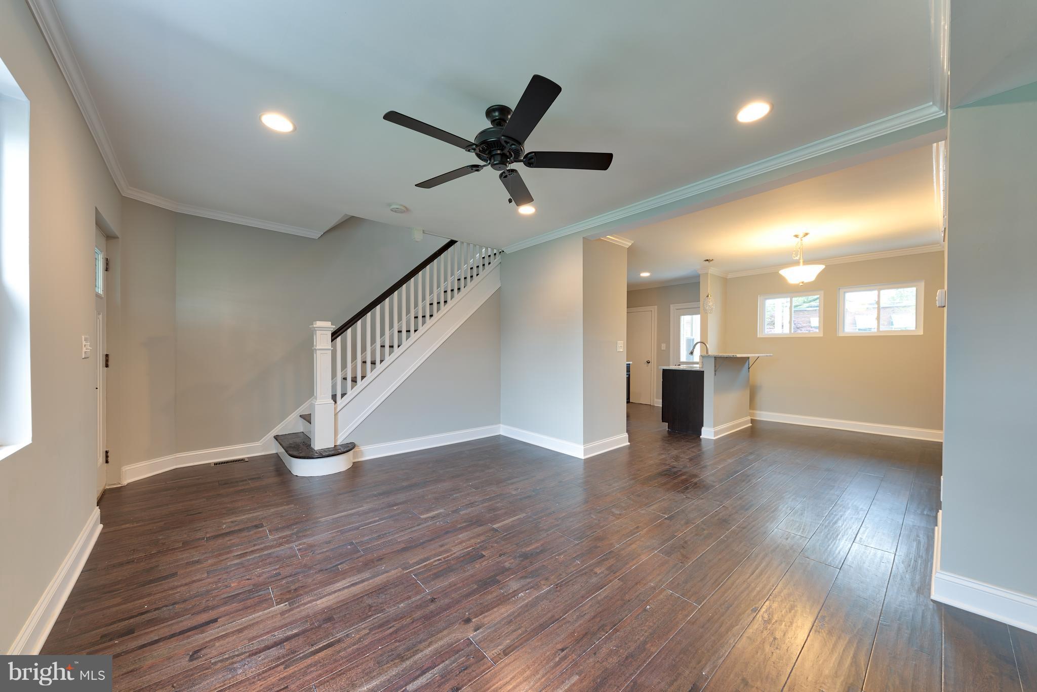 99 Willow Spring Road Baltimore, MD 21222 - Photo 3 of 30 a view of an empty room with wooden floor a ceiling fan and windows