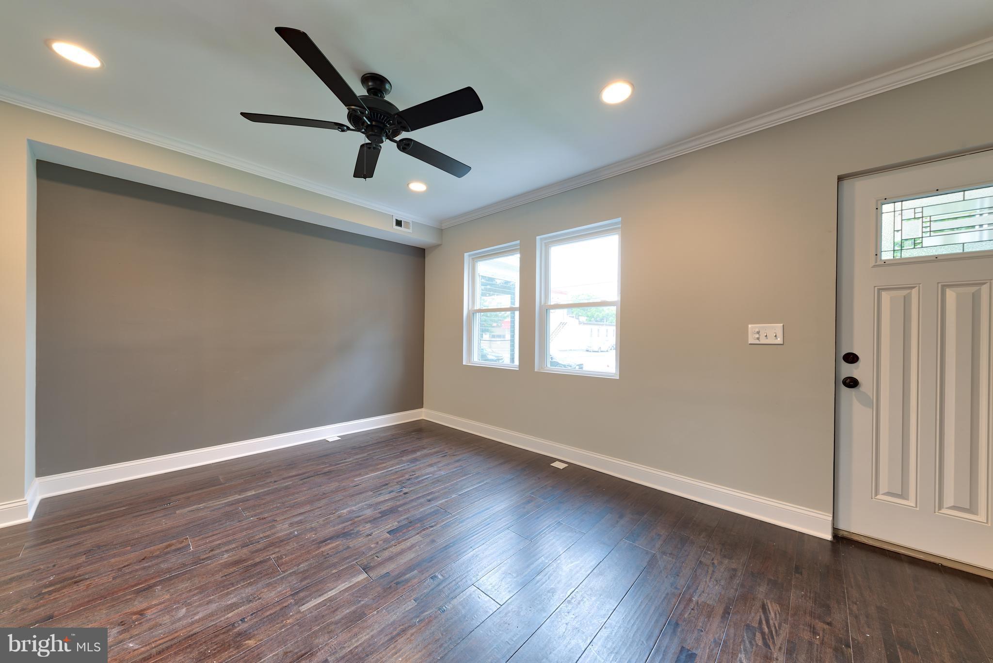 99 Willow Spring Road Baltimore, MD 21222 - Photo 7 of 30 an empty room with wooden floor fan and windows