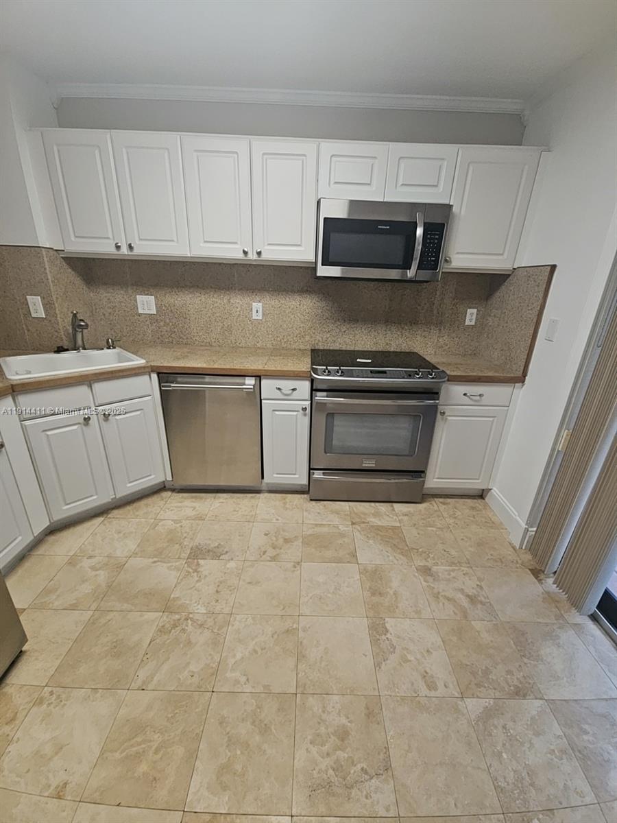 7870 Southwest 102nd Lane Miami, FL 33156 - Photo 11 of 41 a kitchen with granite countertop a stove sink and cabinets