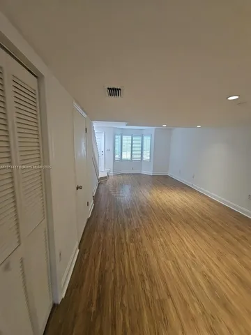 a view of wooden floor in an empty room with a window