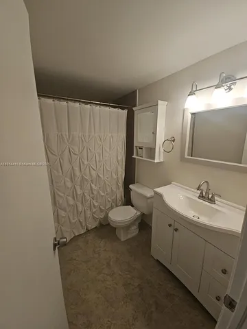 a bathroom with a granite countertop sink toilet and a mirror