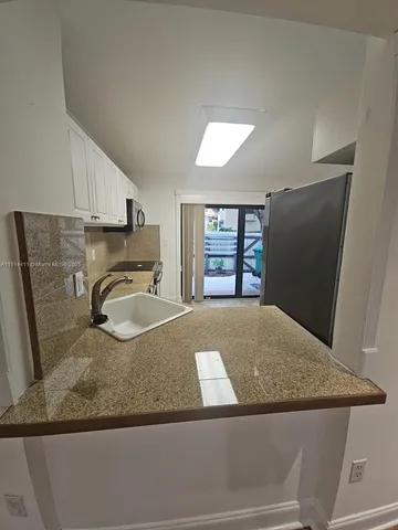 a kitchen with a granite countertop sink and a refrigerator