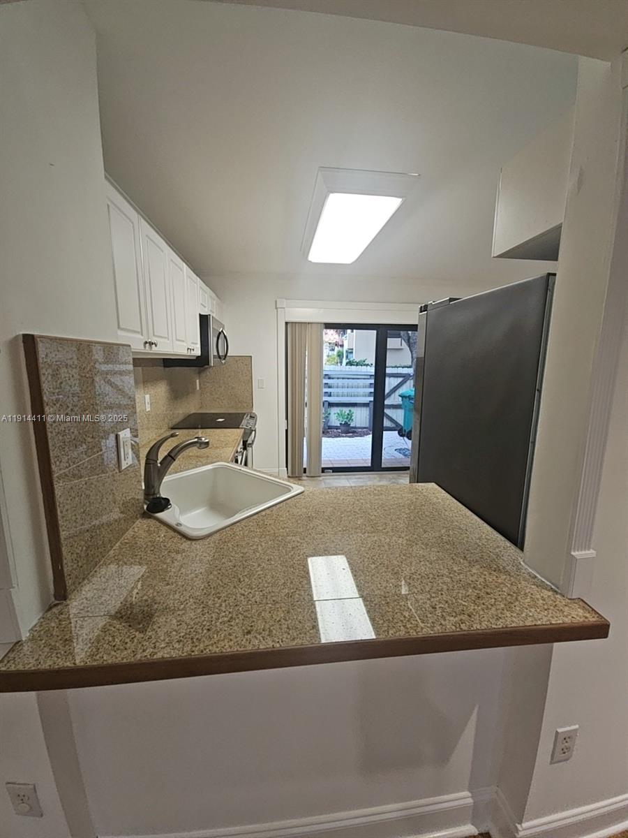 7870 Southwest 102nd Lane Miami, FL 33156 - Photo 9 of 41 a kitchen with a granite countertop sink and a refrigerator