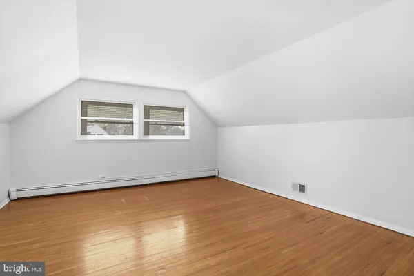 an empty room with a wooden floor and windows