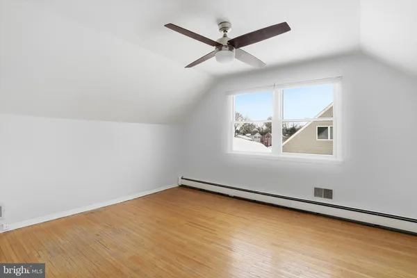 an empty room with wooden floor ceiling fan and windows
