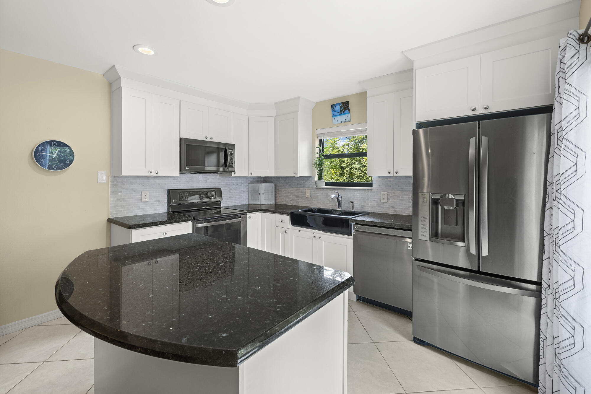 110 North Delaware Boulevard, Unit 18A Jupiter, FL 33458 - Photo 10 of 30 a kitchen with stainless steel appliances granite countertop a sink a stove a refrigerator a microwave a stove and a refrigerator