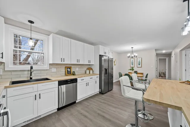 a kitchen with a sink a refrigerator and chairs