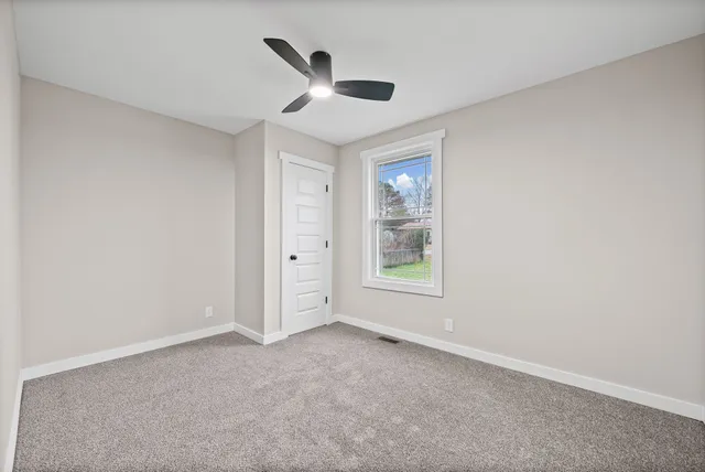 an empty room with windows and ceiling fan