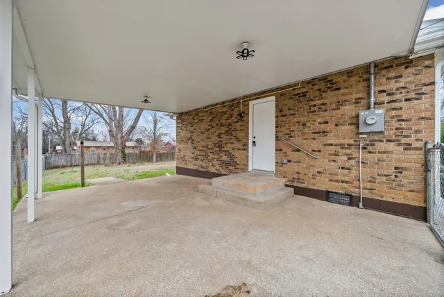 a view of an empty room with a yard and wooden fence