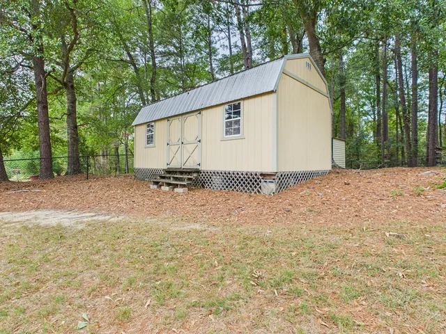 a view of backyard with large tree and wooden fence