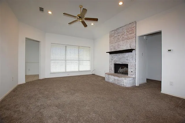a view of an empty room with a fireplace and a window