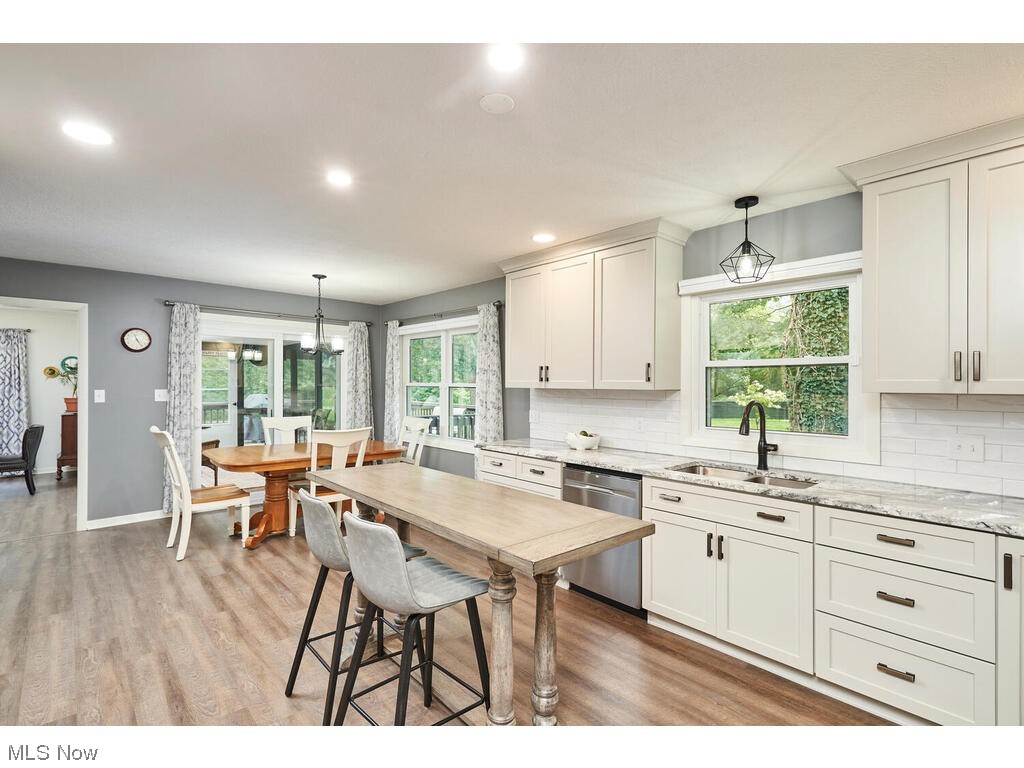 5535 River Styx Road Medina, OH 44256 - Photo 11 of 27 Kitchen featuring stainless steel dishwasher, bright cabinetry, pendant lighting, light granite countertops, luxury vinyl flooring, and backsplash