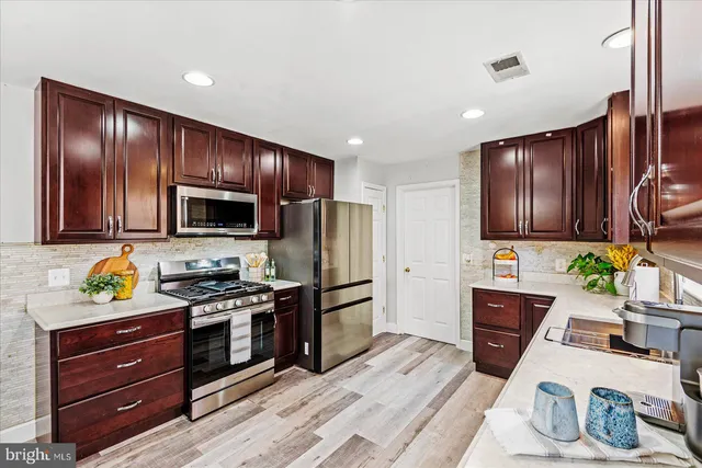a kitchen with stainless steel appliances wooden cabinets and stove top oven