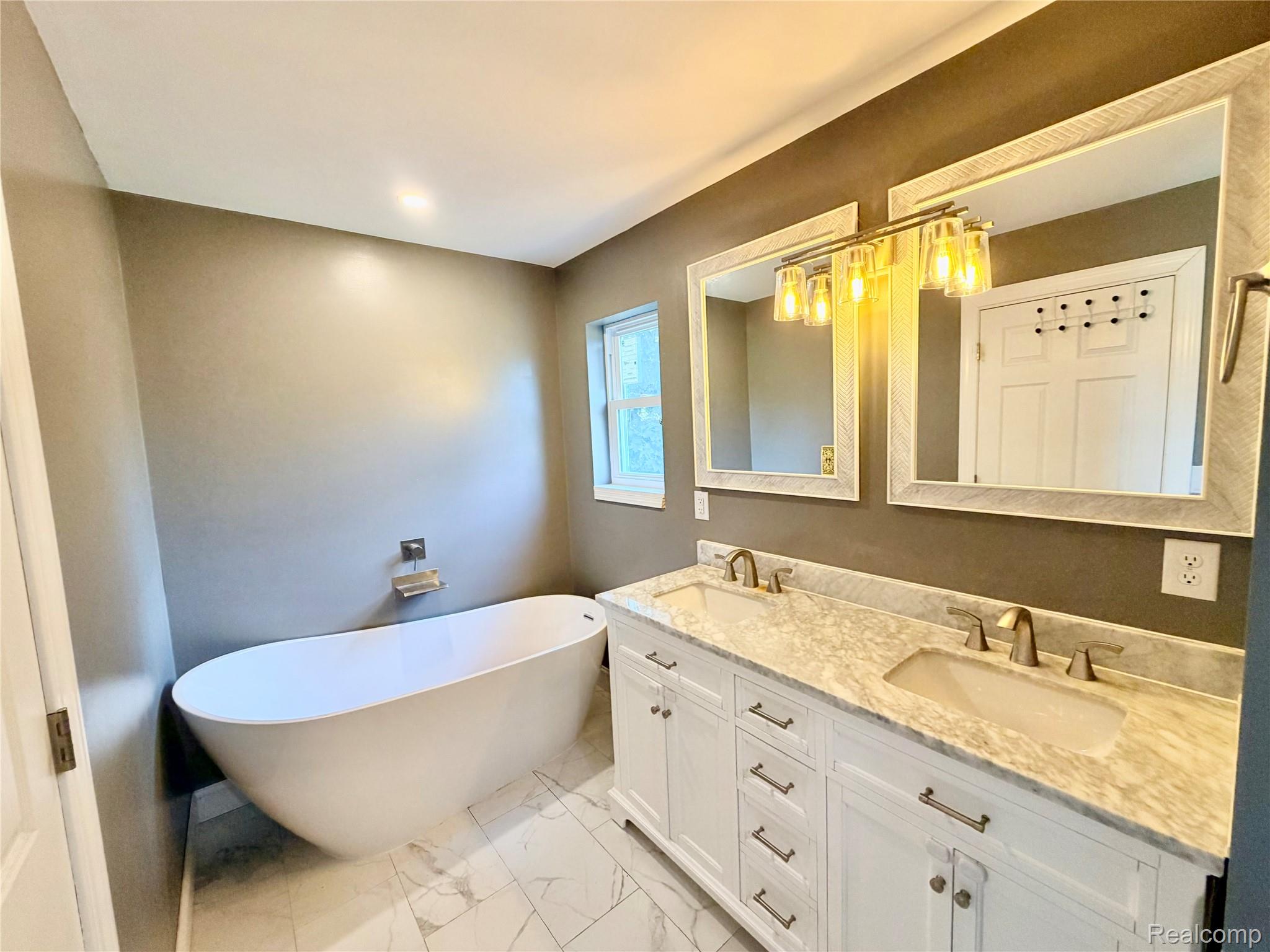 3840 East Dunbar Road Monroe, MI 48161 - Photo 25 of 38 Contemporary bathroom featuring a freestanding soaking tub and a double vanity with a light-toned countertop