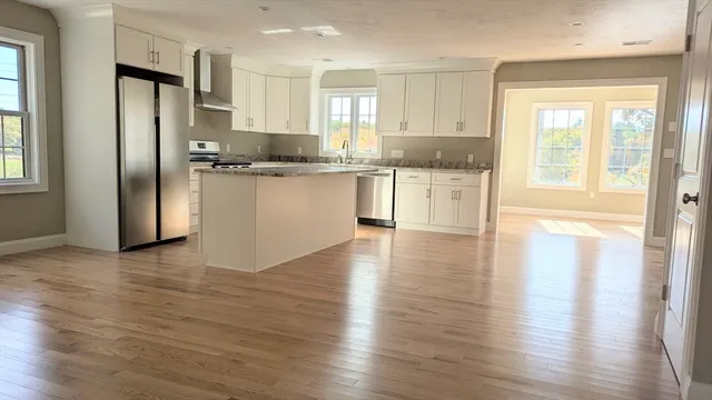 a kitchen with granite countertop wooden floors white cabinets and stainless steel appliances