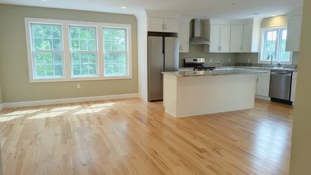 a kitchen with granite countertop a stove a sink dishwasher a refrigerator and cabinets with wooden floor