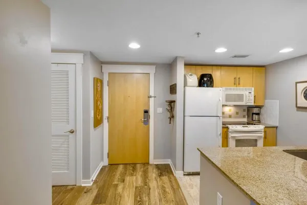 a view of a kitchen with a sink refrigerator and wooden floor