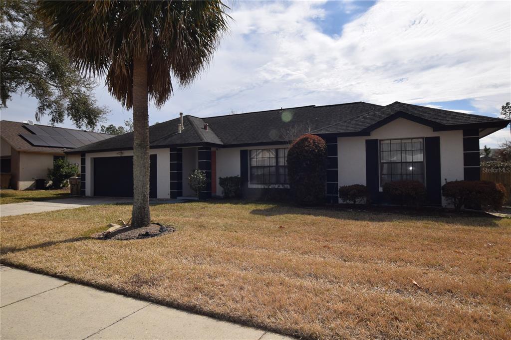 7748 Indian Ridge Trail South Kissimmee, FL 34747 - Photo 3 of 37 a front view of a house with a garden and trees