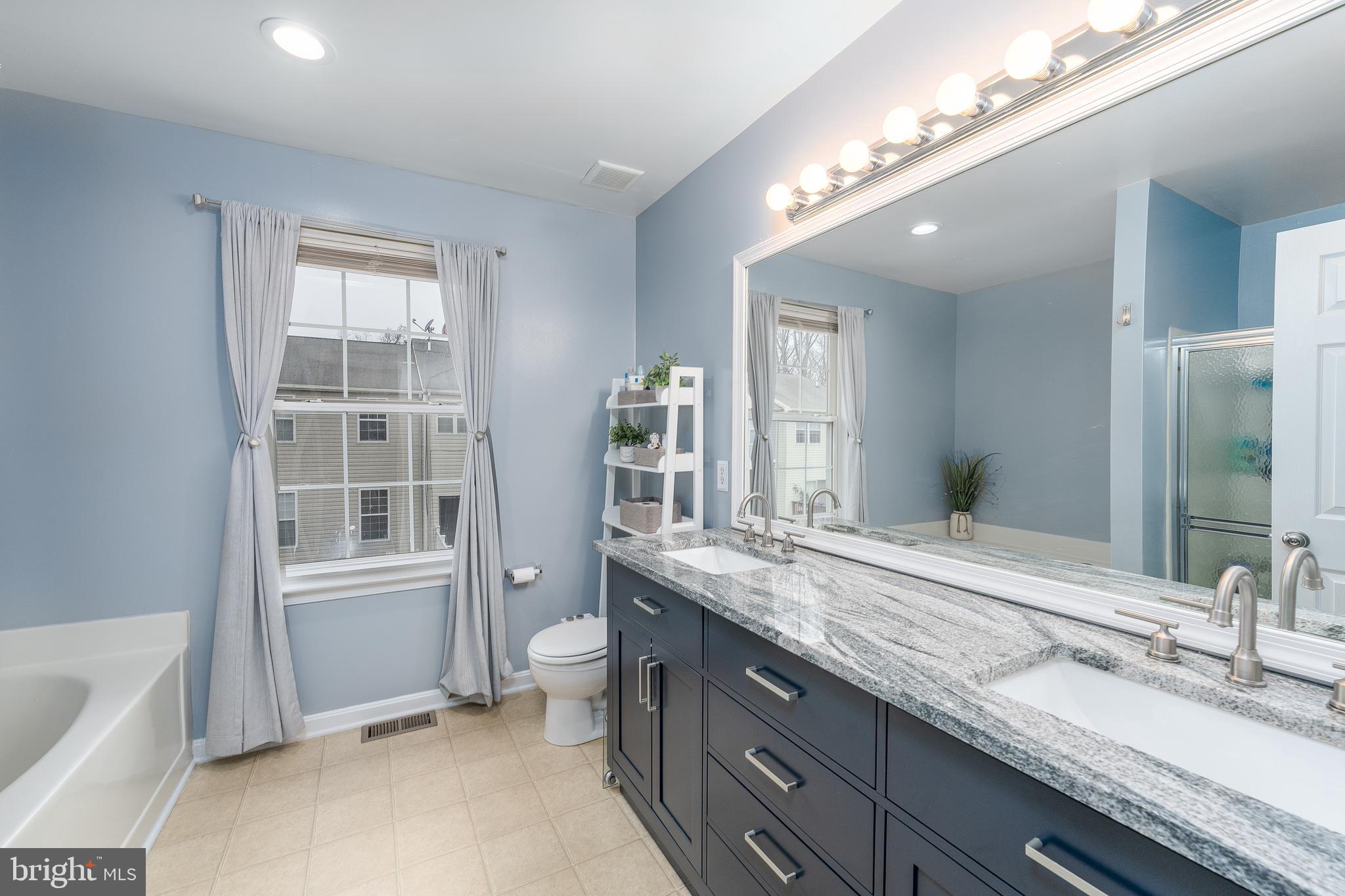 688 Luthardt Road Baltimore, MD 21220 - Photo 24 of 32 a en suite bathroom with a granite countertop double vanity sink a mirror and a bathtub