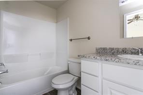 690 Union Street, Unit 2 Bonham, TX 75418 - Photo 11 of 12 a bathroom with a granite countertop toilet a sink and a bathtub