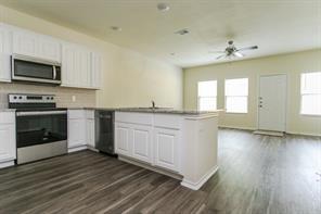 690 Union Street, Unit 2 Bonham, TX 75418 - Photo 5 of 12 a kitchen with granite countertop a stove top oven a sink and dishwasher with wooden floor