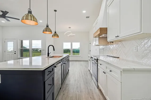 a kitchen with kitchen island granite countertop a sink a stove oven a counter space and cabinets