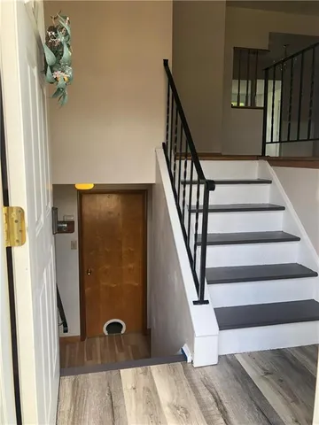 a view of staircase with lots of frames on wall and wooden floor