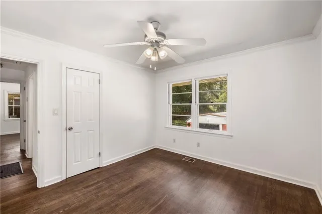 an empty room with wooden floor chandelier fan and windows