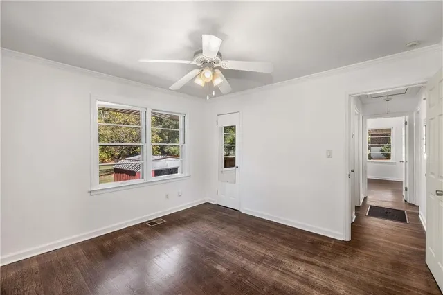 an empty room with wooden floor chandelier fan and windows