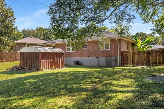 a backyard of a house with table and chairs under an umbrella