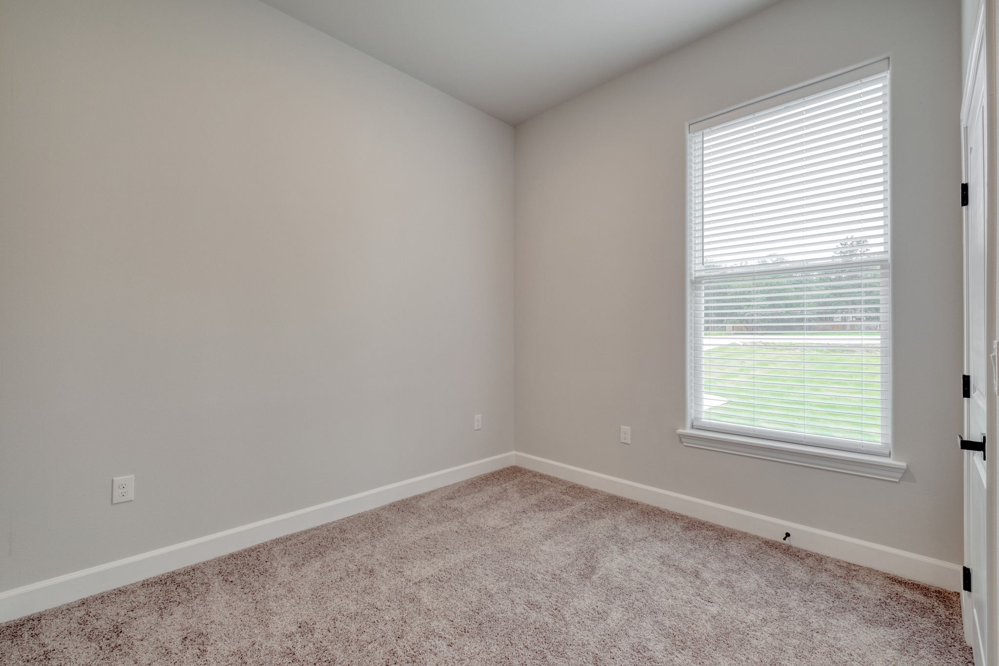 116 Pine Point Cove Elgin, TX 78621 - Photo 19 of 27 Neutral-toned room featuring a single window with blinds, light gray wall paint, white baseboards, and textured carpet flooring
