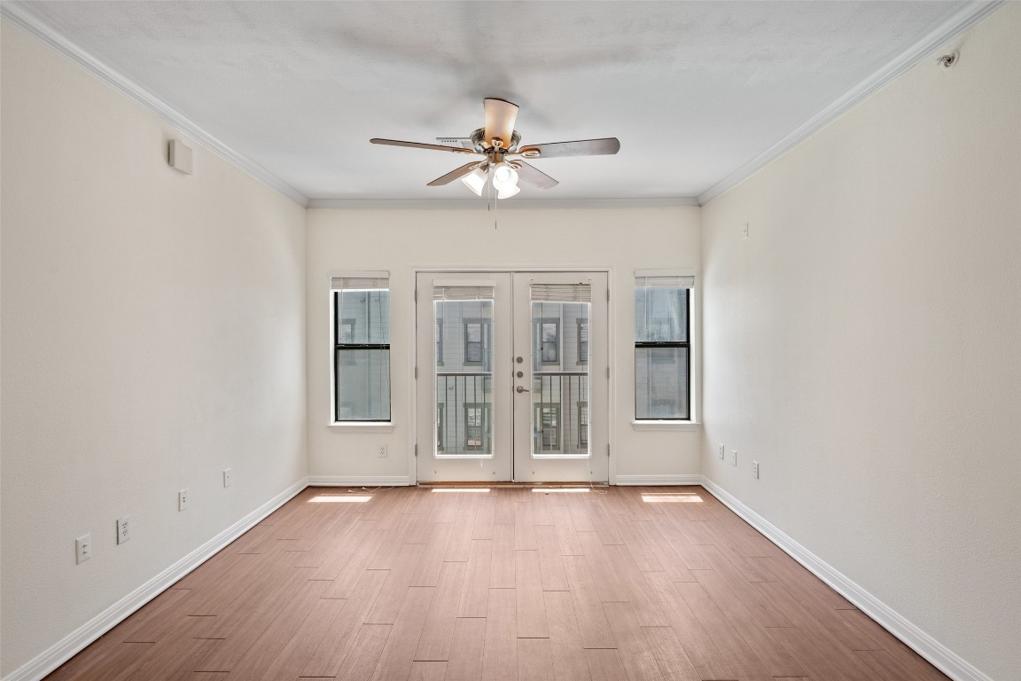 2502 Leon Street, Unit 417 Austin, TX 78705 - Photo 13 of 30 an empty room with wooden floor chandelier fan and windows
