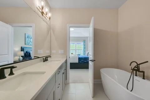 a en suite bathroom with a granite countertop tub a double vanity sink and mirror