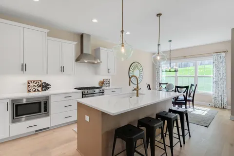 a kitchen with stainless steel appliances a stove a sink a dining table and chairs