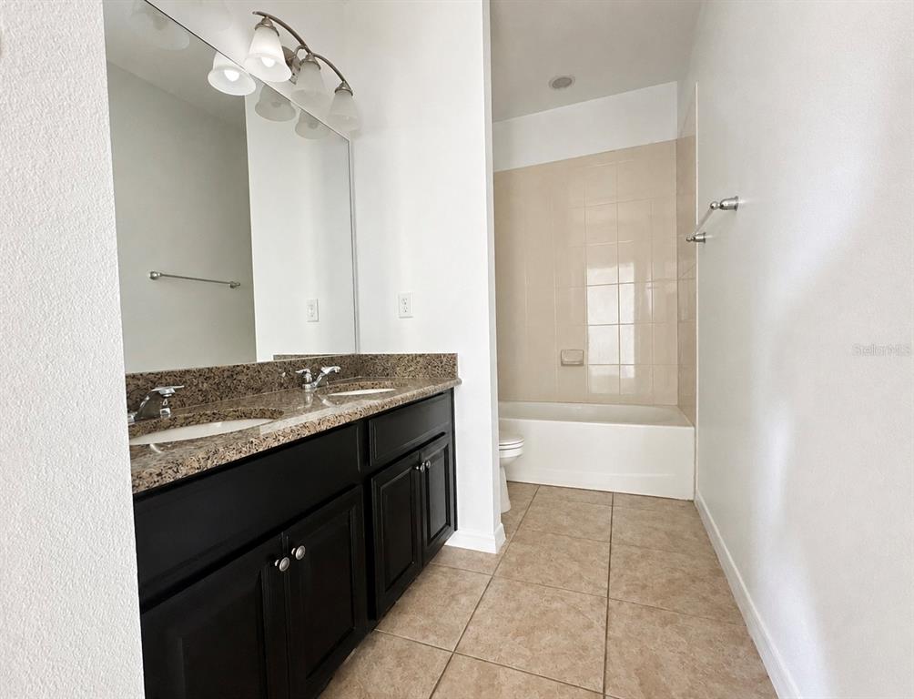 8531 Geddes Loop Orlando, FL 32836 - Photo 15 of 20 a bathroom with a granite countertop sink a toilet and mirror