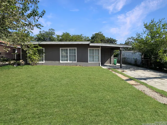 a front view of house with yard and trees in the background
