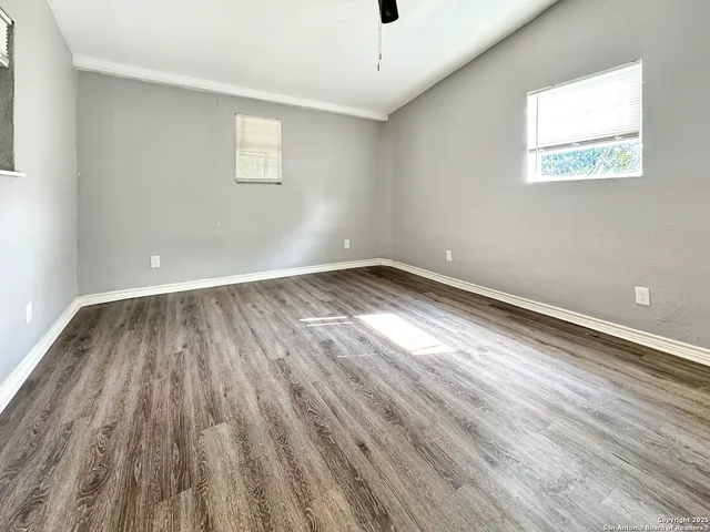 an empty room with wooden floor and windows