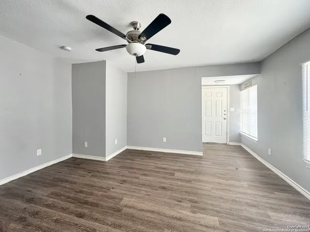 an empty room with wooden floor and windows
