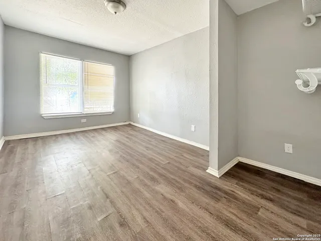 an empty room with wooden floor and windows