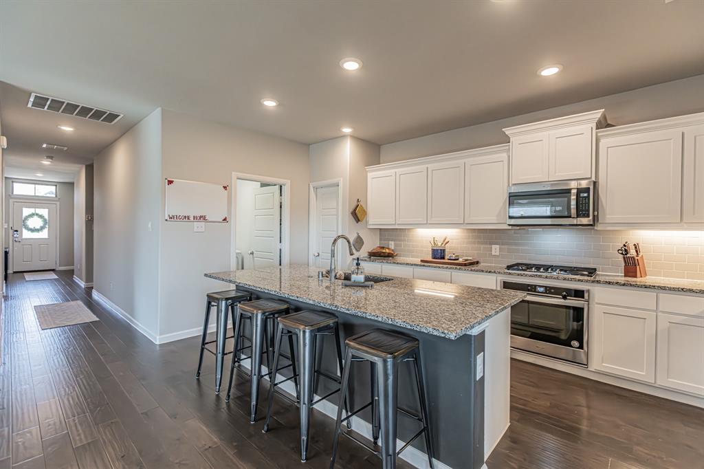 10269 Hanks Creek Road Fort Worth, TX 76126 - Photo 26 of 40 a kitchen with stainless steel appliances granite countertop a stove top oven a sink dishwasher a dining table and chairs with wooden floor