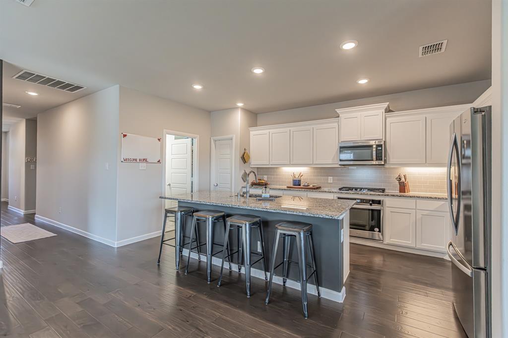 10269 Hanks Creek Road Fort Worth, TX 76126 - Photo 27 of 40 a kitchen with stainless steel appliances granite countertop a refrigerator a stove a sink and white cabinets with wooden floor