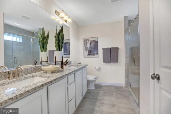 a bathroom with a granite countertop sink mirror vanity and toilet