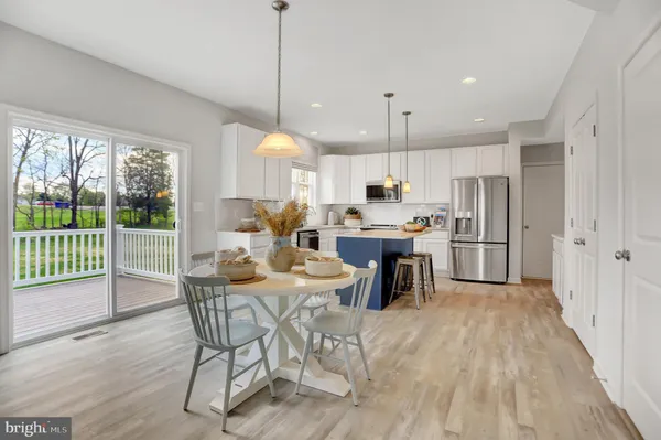 a kitchen with stainless steel appliances kitchen island granite countertop a dining table chairs and white cabinets