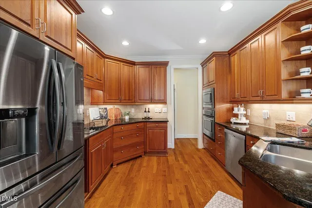 a kitchen with stainless steel appliances granite countertop a refrigerator a stove top oven and sink