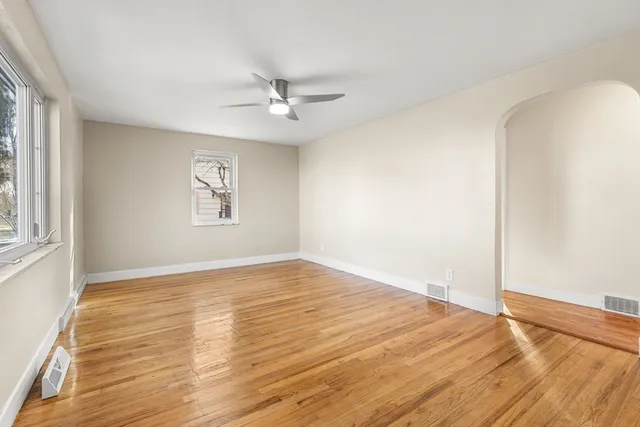 a view of empty room with wooden floor and fan