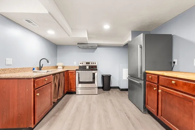 a large kitchen with stainless steel appliances a large counter top a stove and a sink