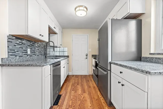 a kitchen with granite countertop a sink stove and refrigerator