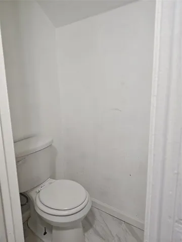 a white toilet sitting next to a white wall