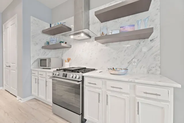 a kitchen with stainless steel appliances granite countertop a stove and a white cabinet