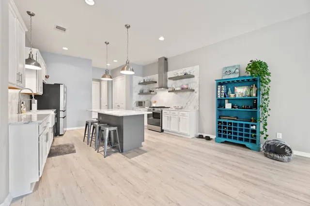 a kitchen with granite countertop a refrigerator a stove a sink dishwasher and white cabinets with wooden floor